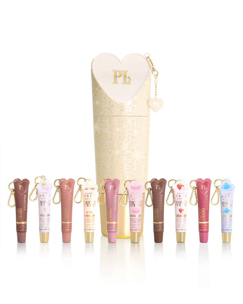 Ein Satz P.Louise Protect Your Pout Lip Conditioner-Tuben in verschiedenen Farbtönen, angeordnet vor einem hohen, glitzernden cremefarbenen zylindrischen Etui mit herzförmigem Reißverschlussschieber. An jeder Röhre ist ein kleiner goldener Schlüsselanhänger befestigt.