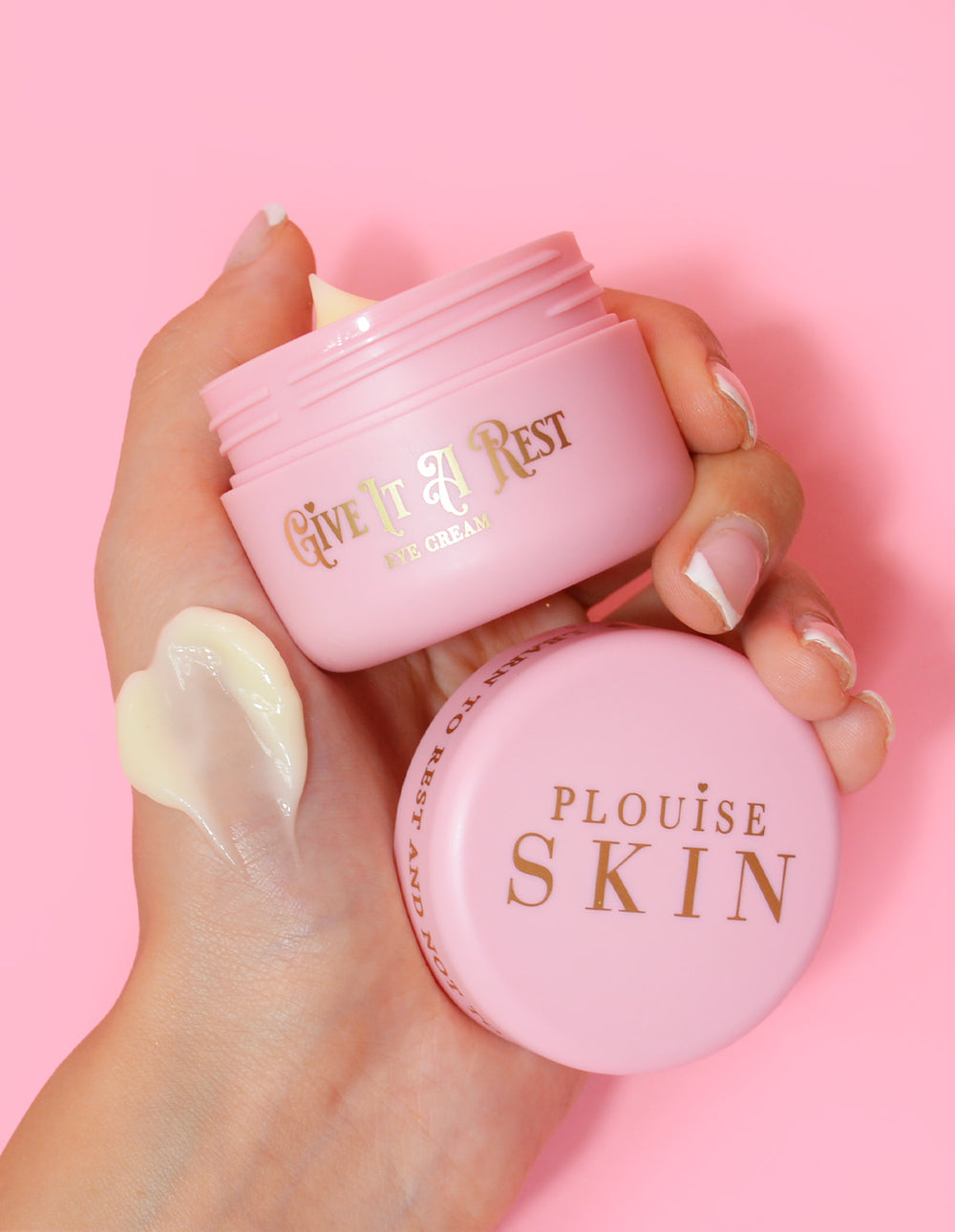 Una persona sosteniendo un frasco rosa de crema para ojos P.Louise Give It A Rest sin la tapa, mostrando el nombre del producto y la marca en el frasco.