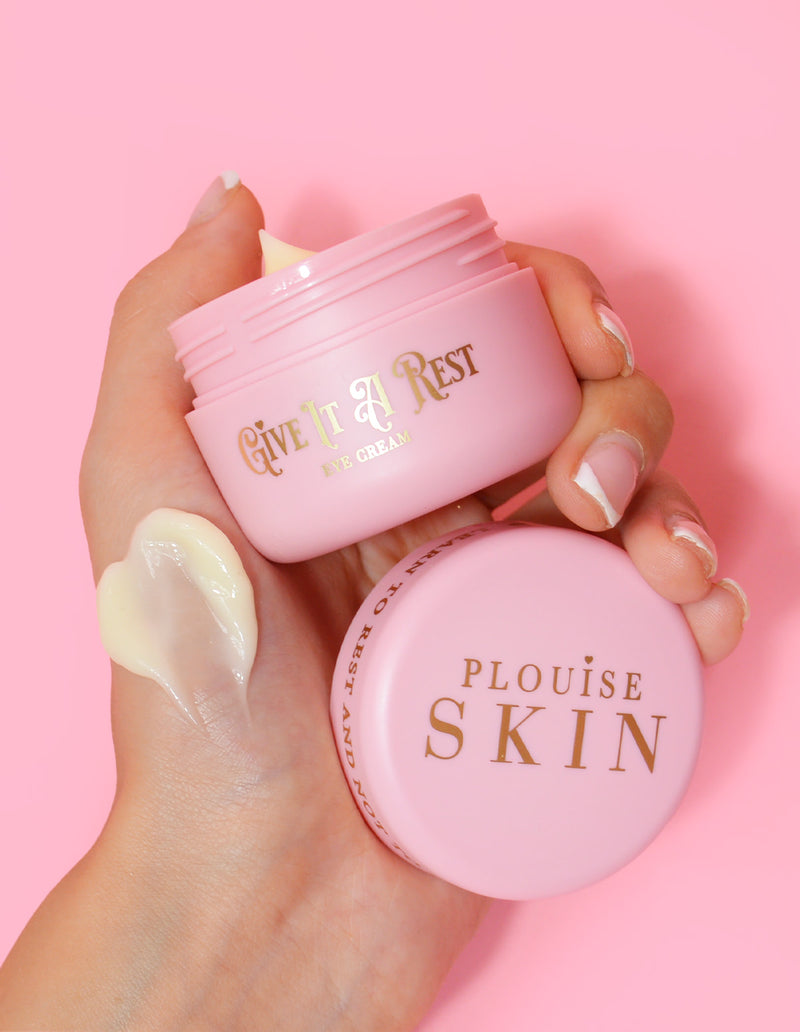 Eine Person hält ein rosafarbenes Glas Augencreme „P.Louise Give It A Rest“ mit abgenommenem Deckel in der Hand, auf dem der Produktname und die Marke zu sehen sind.