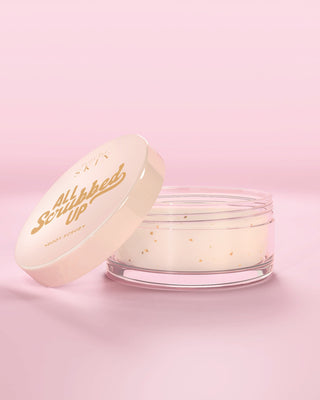 Glas mit P.Louise All Scrubbed Up Body Scrub in Kokosnusskuchen vor rosa Hintergrund