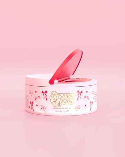 Tarrina rosa de P.Louise Bright By Night Brightening Cream con elementos gráficos de lazo rojo sobre un fondo rosa
