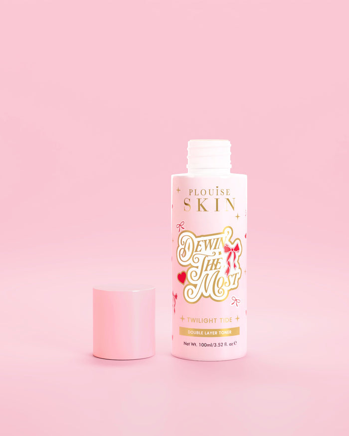 Botella rosa de P.Louise Dewin The MOst Double Layer Toner con diseños de lazos rojos sobre un fondo rosa 