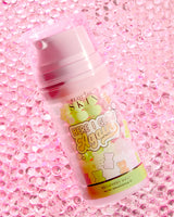 Una botella de P.Louise Here I Glow Again Recovery Mask con aroma a ositos de caramelo con una etiqueta rosa y verde, con ilustraciones de ositos de caramelo, colocadas sobre un fondo rosa brillante.