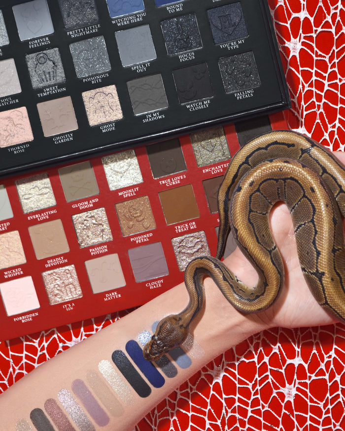 P.Louise Mystic Moonlight Halloween-Lidschatten- und Make-up-Palette mit Farbfeldern auf einem Arm, um den sich eine Schlange vor einem roten Spinnweben-Hintergrund wickelt