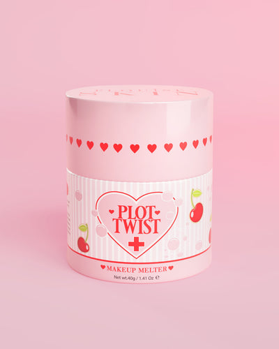 Un recipiente rosa de P.Louise Plot Twist Makeup Melting Cleansing Balm con diseños de corazón y cereza en la etiqueta sobre un fondo rosa