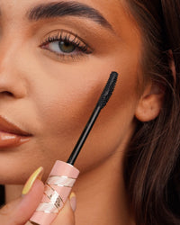 Nahaufnahme eines P.Louise Tearproof Mascara-Stabs, der in die Nähe des Auges einer Person gehalten wird, mit verschwommenem Hintergrund