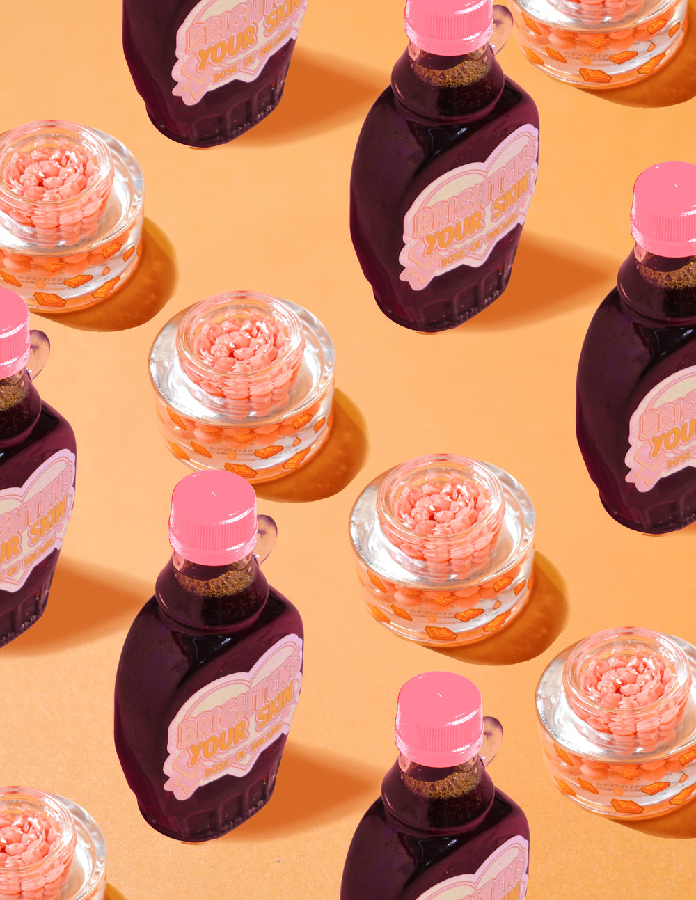Envases transparentes de P.Louise Dose of Dreams Vitamin C Capsule Cream con cápsulas de color naranja en su interior rodeadas de botellas de jarabe de color púrpura y rosa sobre un fondo naranja