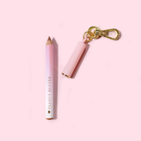 Mini llavero delineador de labios rosa de P.Louise con la marca 'Peanut Butter' sobre un fondo rosa claro