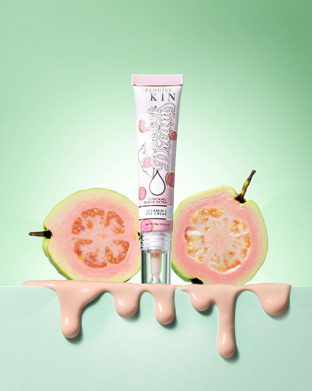 Tubo de P.Louise Dose Of Dreams Vitamin C Brightening Eye Cream rodeado de fruta de guayaba sobre un fondo verde