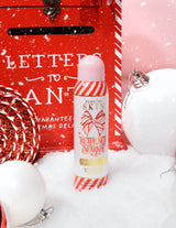 Eine Flasche P. Louise Ready Set Sparkle Christmas Glitter Setting Spray, umgeben von festlichen Dekorationen wie Schnee, Kugeln und einem Weihnachtsbriefkasten