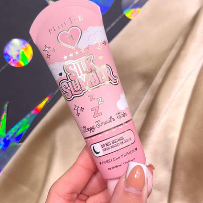 Eine Person hält eine Tube P.Louise Silk Slumber Poreless Primer mit rosa Hintergrund und Kosmetikproduktdetails.