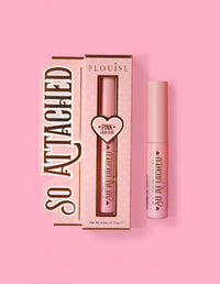 Die Produktverpackung von P.Louise So Attached Lash Glue und die Klebetube selbst vor einem rosa Hintergrund.