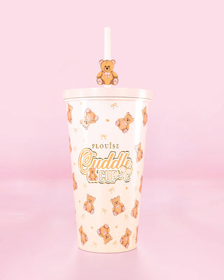 Vaso con pajita y diseño de osito de peluche con el texto 'Cuddle Cup' sobre fondo rosa